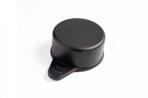 A black plastic cap sitting on top of a white table.