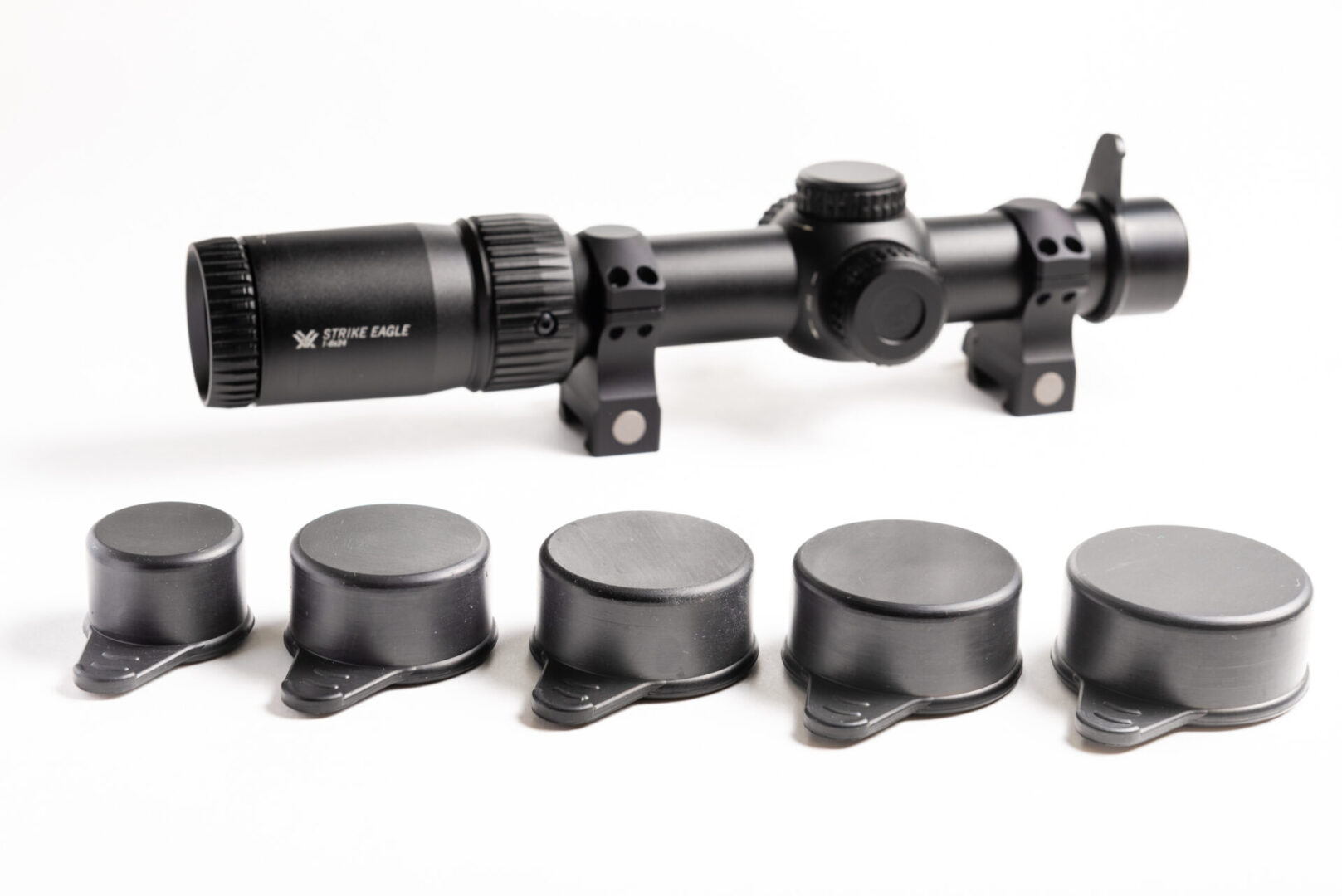 A rifle scope and seven different sized caps.